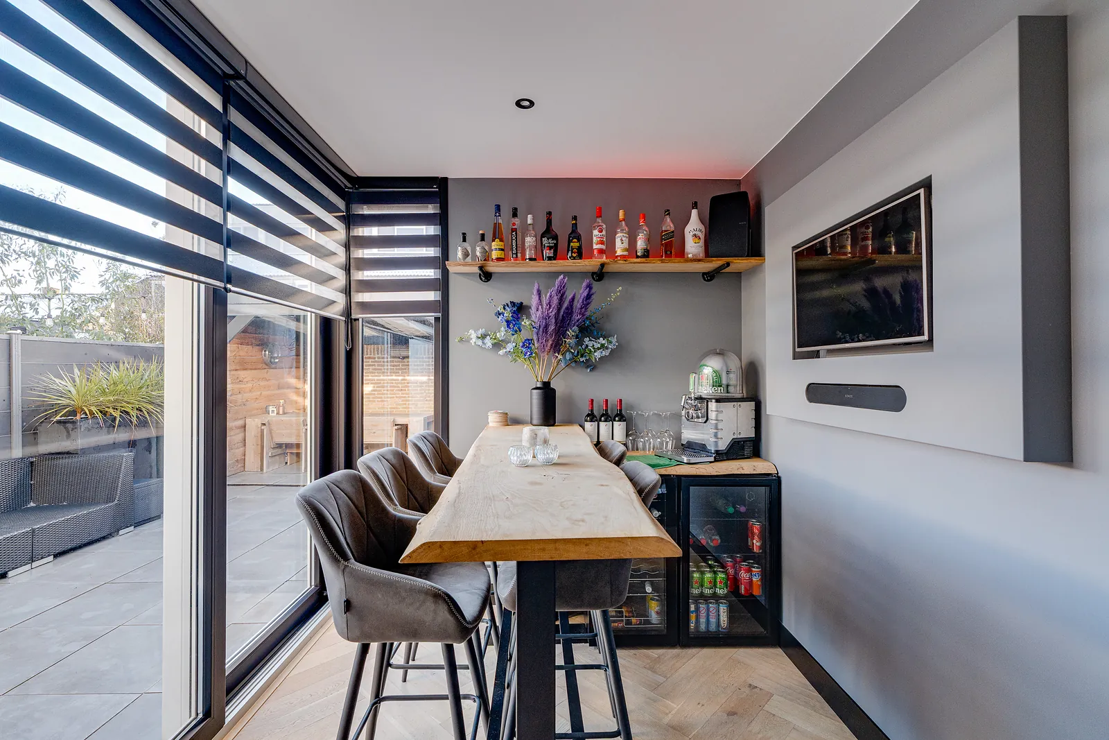 Bar met hoge krukken naast een dakterras met loungeset